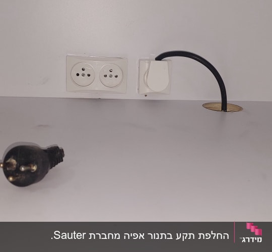 שקע חשמל כפול וכבל שחור על שולחן לבן
